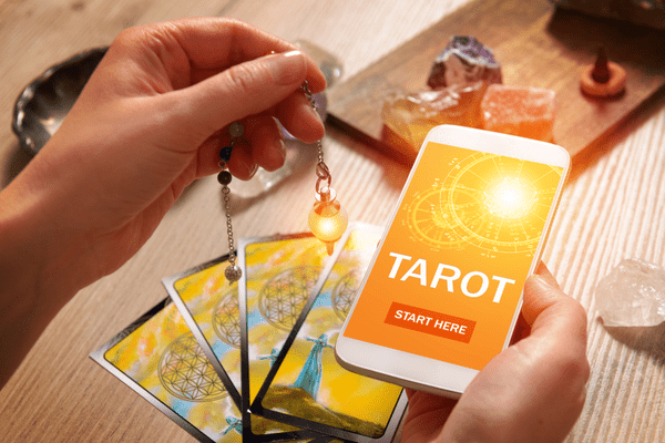 tarot-cards-on-the-table-and-a-woman-holding-a-smartphone-with-fortunetelling-application